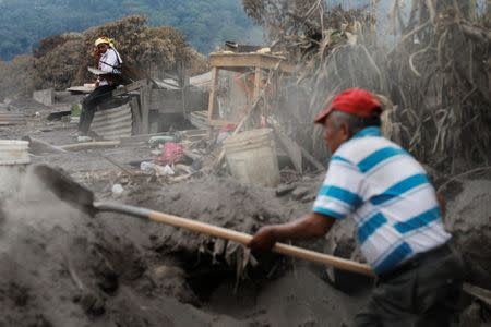 Eufemia Garcia, 48, who lost 50 members of her family during the eruption of the Fuego volcano, observes a volunteer who is aiding her in the search for her family in San Miguel Los Lotes in Escuintla, Guatemala, June 11, 2018. REUTERS/Carlos Jasso