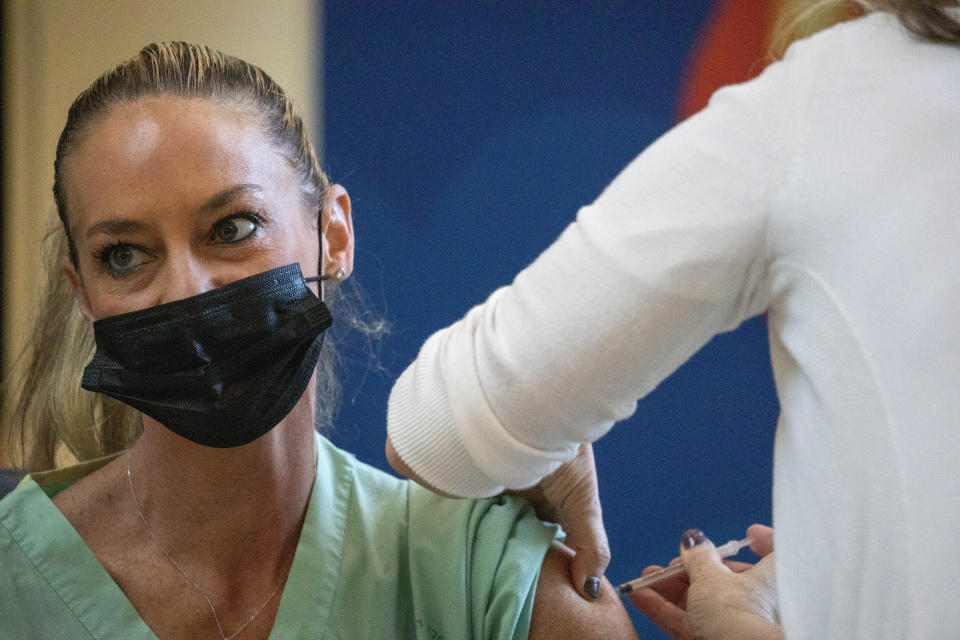 A medical staff receives a COVID-19 coronavirus vaccine at the Ichilov Hospital in Tel Aviv, Israel, Sunday, Dec. 20, 2020. (AP Photo/Ariel Schalit)