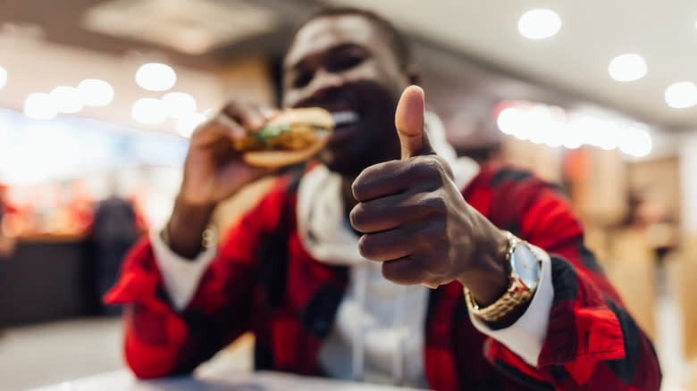 man eating burger thumbs up