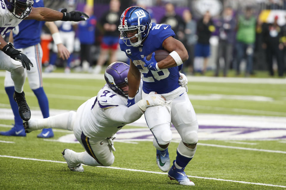 New York Giants running back Saquon Barkley (26) tries to break a tackle by Minnesota Vikings defensive tackle Harrison Phillips (97) during the second half of an NFL football game, Saturday, Dec. 24, 2022, in Minneapolis. (AP Photo/Bruce Kluckhohn)