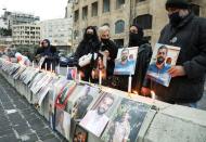 Relatives of victims of Beirut port explosion, hold their pictures during a protest demanding justice, at the entrance of Beirut port