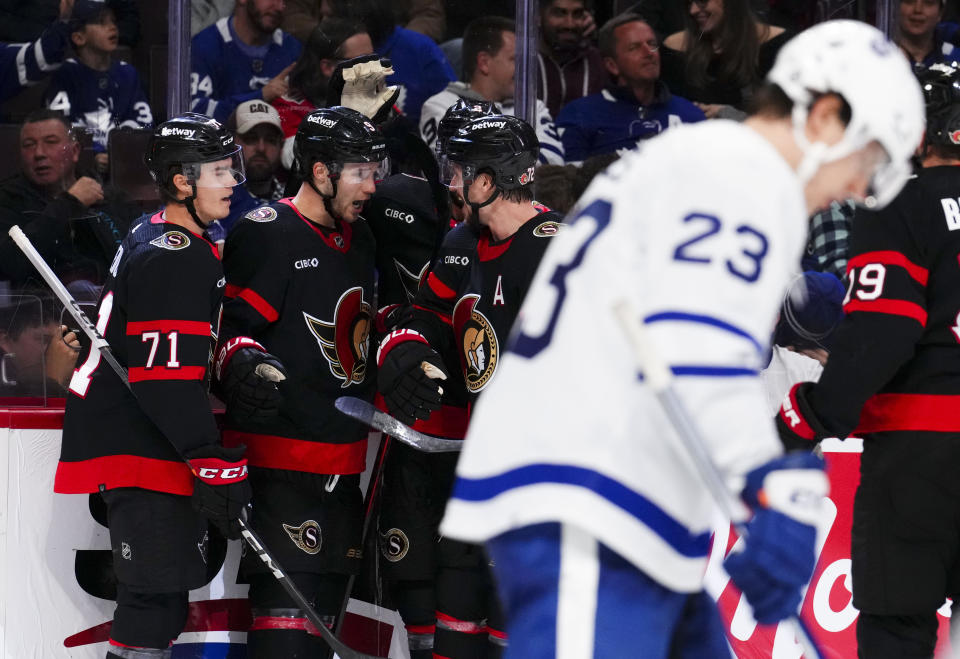 Ottawa Senators center Josh Norris (9) celebrates after his goal with teammates as Toronto Maple Leafs left wing Matthew Knies (23) skates past during second-period NHL hockey game action in Ottawa, Ontario, Saturday, Feb. 10, 2024. (Sean Kilpatrick/The Canadian Press via AP)