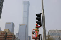 A worker installs new traffic lights at a junction in Beijing on Thursday, April 15, 2021. China’s economic growth surged to 18.3% over a year earlier in the first quarter of this year as factory and consumer activity recovered from the coronavirus pandemic. (AP Photo/Ng Han Guan)