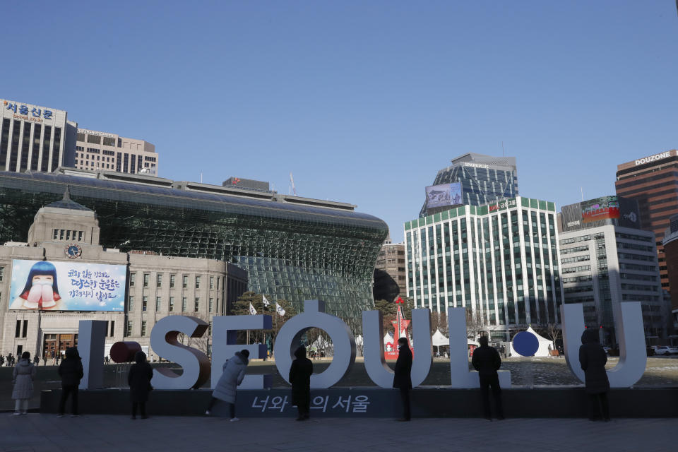 People queue in line to wait for a coronavirus test near a display of South Korea's capital Seoul logo in Seoul, South Korea, Thursday, Dec. 17, 2020. South Korea has added more than 1,000 infections to its coronavirus caseload for the second straight day amid growing fears that the virus is spreading out of control in the greater capital area. (AP Photo/Lee Jin-man)