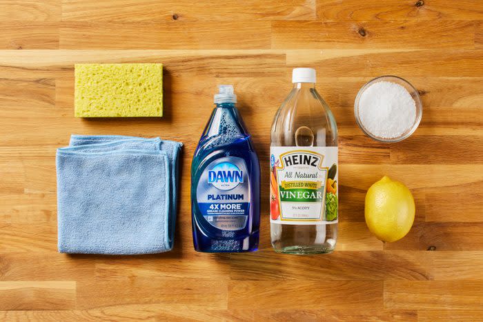 Butcher Block Wood countertop with sponge, cleaning cloth, dish soap, vinegar, small bowl of salt, and a lemon