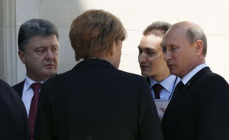 Ukraine president-elect Petro Poroshenko (L), German Chancellor Angela Merkel (C) and Russian President Vladimir Putin (R) talk after a group photo during the 70th anniversary of the D-Day landings in Benouville, France June 6, 2014. REUTERS/Kevin Lamarque