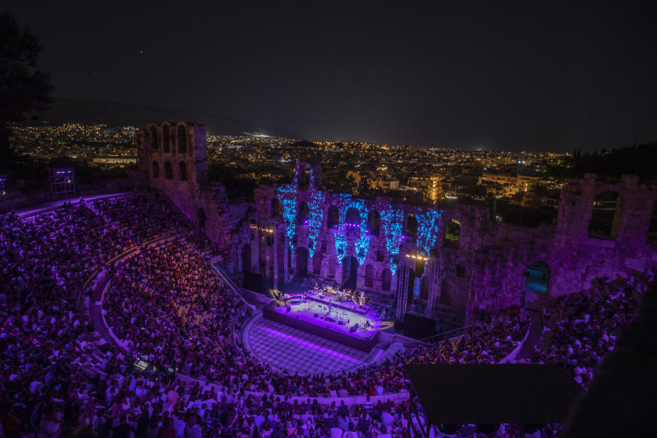 Spectators listen a concert at Odeon of Herodes Atticus as the city of Athens is seen on the background on Wednesday, July 15, 2020. The ancient theaters of Herodes Atticus in Athens and Epidaurus in the southern Peloponnese area have reopened for performances with strict seating limits and public health safety guidelines. (AP Photo/Petros Giannakouris)