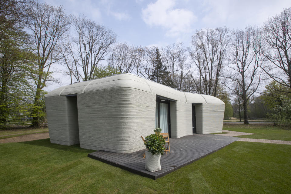 Exterior view showing the printer layers in the walls of the 3D-printed 94-square meters (1,011-square feet) two-bedroom bungalow resembling a boulder with windows in Eindhoven, Netherlands, Friday, April 30, 2021. The fluid, curving lines of its gray walls look natural. But they are actually at the cutting edge of housing construction in the Netherlands and around the world. They were 3D printed at a nearby factory. (AP Photo/Peter Dejong)