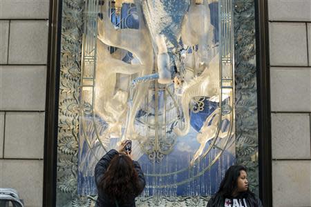 A woman stops to take a picture with her cell phone of a holiday window display at the Bergdorf Goodman store in New York, November 22, 2013. REUTERS/Lucas Jackson