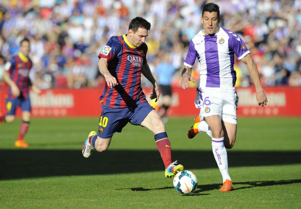 Barcelona's Lionel Messi from Argentina, left, and Valladolid's defender Jesus Rueda challenge for the ball during a Spanish La Liga soccer match at the Jose Zorrilla stadium in Valladolid, Spain, Saturday March 8, 2014. (AP Photo/Israel L. Murillo)
