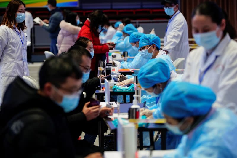 People fill forms before receiving a dose of a coronavirus disease (COVID-19) vaccine at a vaccination site, in Shanghai