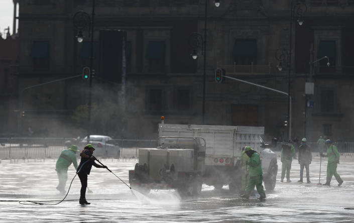 City workers hose down the capital's main square the Zocalo in Mexico City, Monday, June 29, 2020. Mexico City is moving this week to the next stage of its gradual reopening from its COVID-19 pandemic lockdown. (AP Photo/Eduardo Verdugo)
