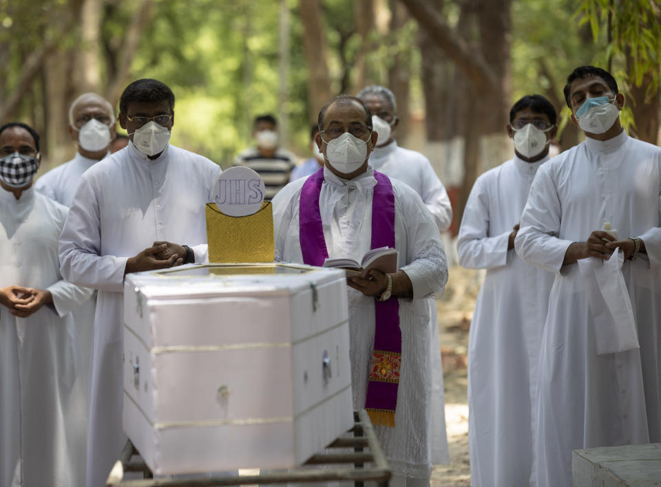 Indian Christian priests offer prayers next to the coffin of Father Rolfie D'Souza's who died of COVID-19, at a cemetery in Prayagraj, India, Saturday, May 15, 2021. India's Prime Minister Narendra Modi on Friday warned people to take extra precautions as the virus was spreading fast in rural areas. (AP Photo/Rajesh Kumar Singh)