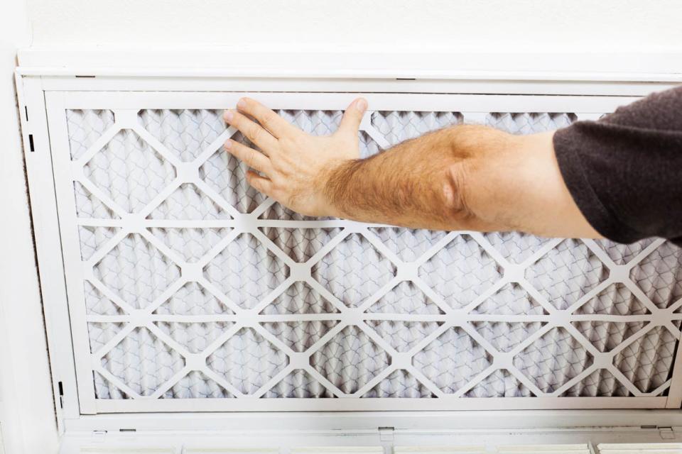 A close up of a person holding an air filter in place.