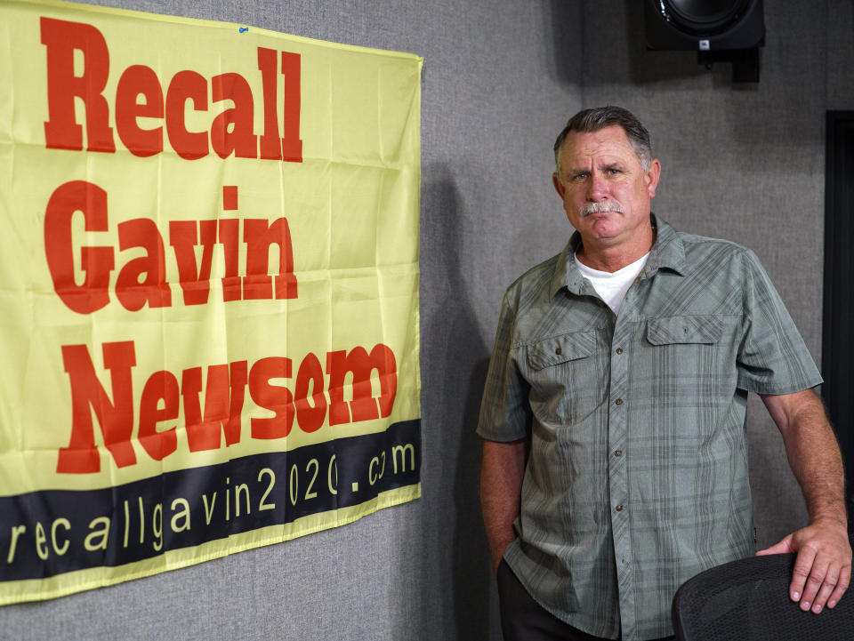 FILE — In this March 27, 2021, file photo Orrin Heatlie, the main organizer for the Recall of California Gov. Newsom campaign, poses with a banner before recording a radio program at KABC radio station studio in Culver City, Calif. Newsom is facing the second recall of a governor in California history, and the last day to vote is Sept. 14, 2021. The coronavirus has been a dominating factor in the recall, which was first launched last year. (AP Photo/Damian Dovarganes, File)