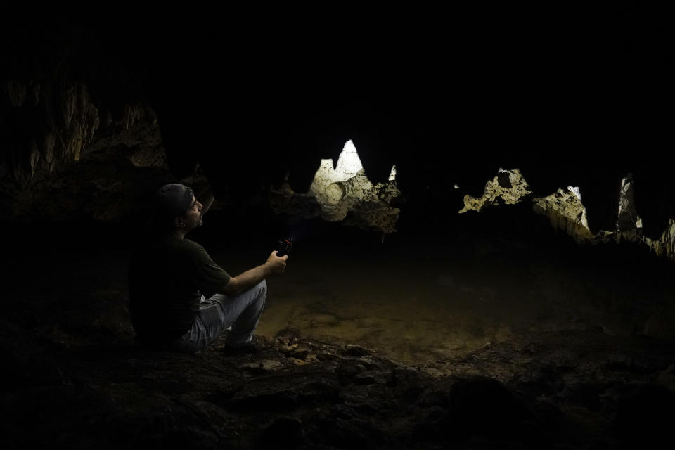 El arqueóloco Octavio del Río apunta con su linterna hacia las paredes de la cueva Guardianes, una caverna subterránea inundada que se extiende varios kilómetros debajo de la ruta que seguirá el Tren Maya bajo construcción en los alrededores de Playa del Carmen (México). El techo de piedra caliza de la cueva tiene menos de un metro de espesor en algunas partes y es casi seguro que se derrumbaría al paso del pesado tren. según del Río. Foto del 1ro de agosto del 2022. (AP Photo/Eduardo Verdugo)