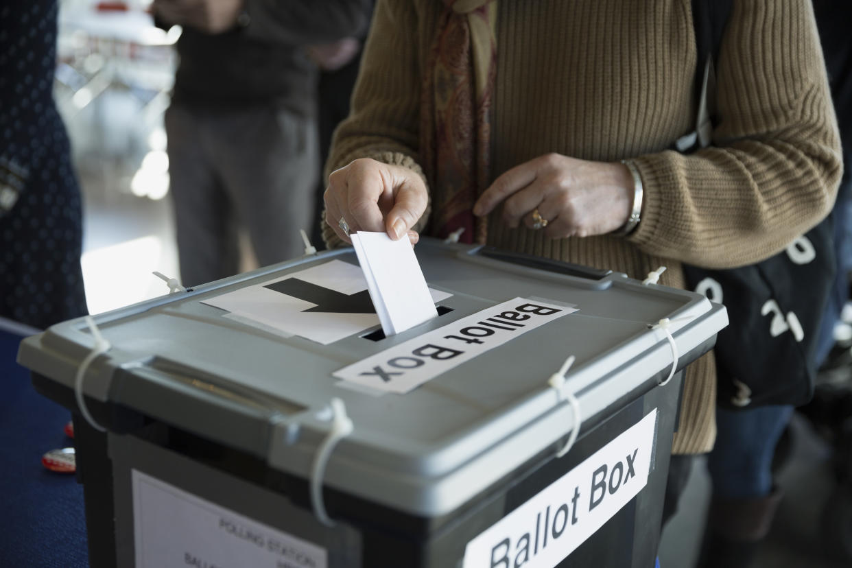 Woman placing ballot in ballot box polling place