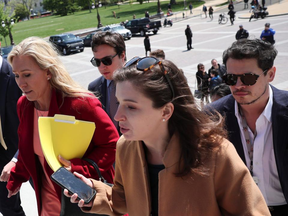 Greene ascends the steps of the Capitol outside the House of Representatives as a reporter asks her questions on April 28, 2022. Yiannopoulos can be see on the right.