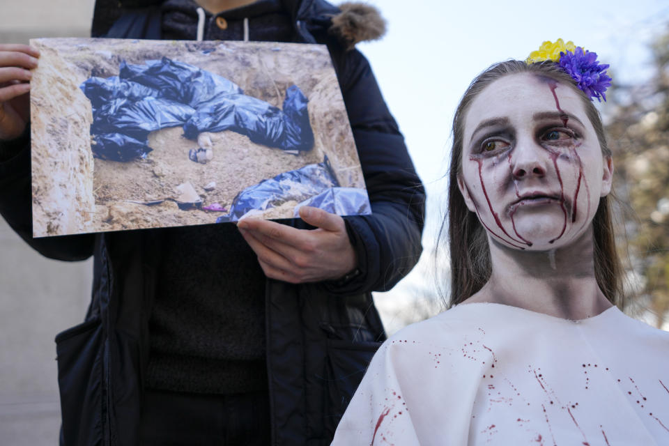 A woman wearing make up to symbolise blood shed, attends a rally to mark the anniversary of the liberation of Bucha, a town outside Kyiv that became a symbol of Russian atrocities against civilians, near the Russian embassy in Belgrade, Serbia, Friday, March 31, 2023. (AP Photo/Darko Vojinovic)