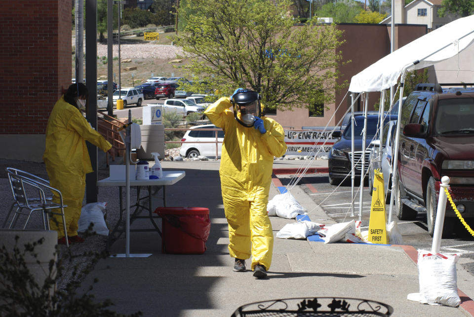 In this May 7, 2020, photo, medical staff from Rehoboth McKinley Christian Hospital put on protective equipment as they work at a drive-thru coronavirus testing site outside the hospital in Gallup, N.M. Of about 500 medical and support staff, at least 32 hospital workers have become infected, and doctors and nurses say that they all live with the fear of spreading the virus to their colleagues and relatives. (AP Photo/Morgan Lee)