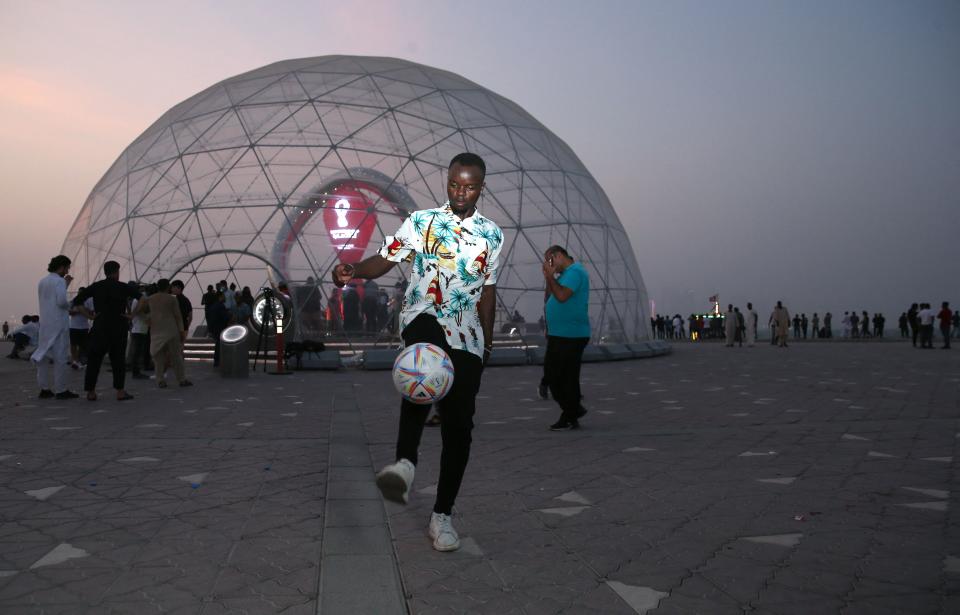 Un joven juega con una pelota de fútbol cerca de la cúpula que alberga el reloj de cuenta regresiva de la Copa Mundial de la FIFA Qatar 2022, en la capital, Doha, el 12 de agosto de 2022, fecha que marca 100 días antes del inicio del evento. La FIFA y los organizadores de Qatar calcularon el costo de adelantar un día el inicio de la Copa del Mundo. mientras lanzaban la cuenta regresiva de 100 días para el evento. (Foto: MUSTAFA ABUMUNES/AFP vía Getty Images)