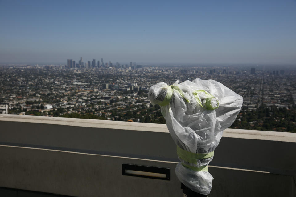 A telescope is seen wrapped in plastic to prevent the spread of COVID-19 at the Griffith Observatory overlooking downtown Los Angeles, Wednesday, July 15, 2020. Coronavirus cases have surged to record levels in the Los Angeles area, putting the nation's largest county in "an alarming and dangerous phase" that if not reversed could overwhelm intensive care units and usher in more sweeping closures, health officials said Wednesday. (AP Photo/Jae C. Hong)