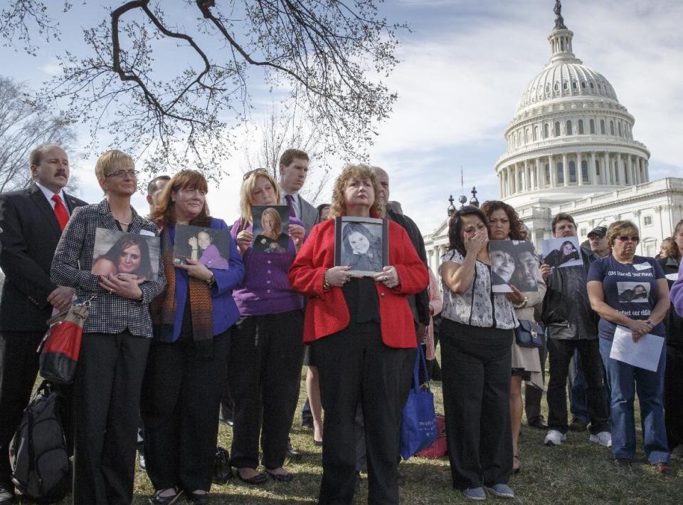 FILE - In this Tuesday, April 1, 2014, file photo families of victims of a General Motors safety defects in small cars hold photos of their loved ones as they gather on the lawn on Capitol Hill in Washington. Families of those who died in General Motors cars with defective ignition switches want prosecutors to go after GM insiders responsible for letting the problems fester for more than decade, and perhaps for covering them up. (AP Photo/J. Scott Applewhite, File)