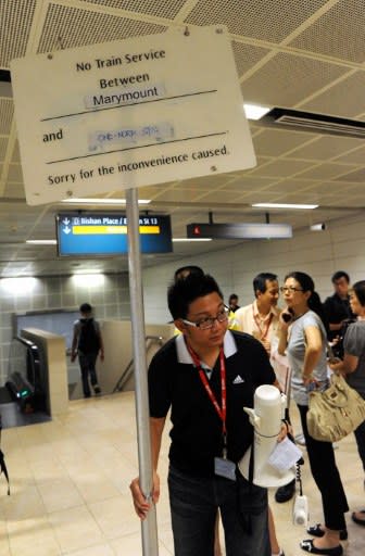 A staff member of the SMRT places a notice board alerting commuters of no train service on the SMRT circle line train between two stations, at a station interchange in Singapore on 18 April. (AFP photo)