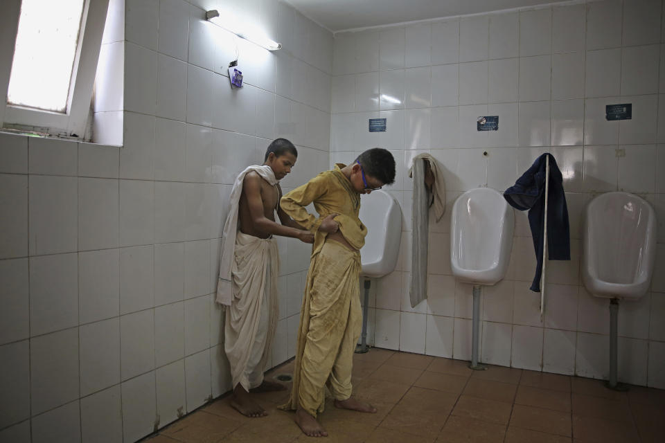 A schoolboy, left, dressed as Mahatma Gandhi helps another dress up as a statue depicting Indian freedom leader Mahatma Gandhi's Dandi March on the eve of Gandhi's 150th birth anniversary in New Delhi, India, Tuesday, Oct. 1, 2019. Dandi March is the name given to the Salt Satyagraha (Salt March) where Gandhi and other freedom fighters marched 241 miles to the sea to make their own salt on April 6, 1930 as an act of civil disobedience against the British colonial rule. (AP Photo/Altaf Qadri)