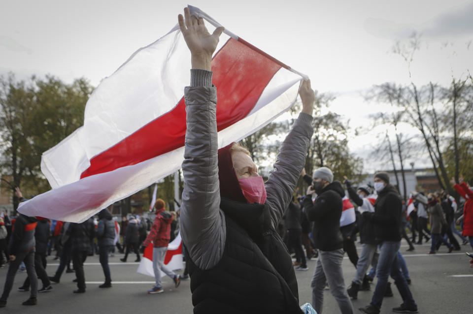 People with old Belarusian national flags march during an opposition rally to protest the official presidential election results in Minsk, Belarus, Sunday, Oct. 18, 2020. Hundreds of thousands of Belarusians have been protesting daily since the Aug. 9 presidential election. (AP Photo)