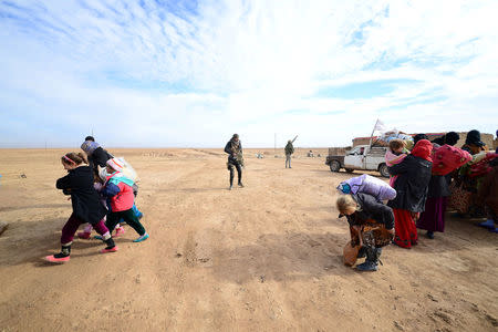 Displaced people, fleeing the violence of Islamic State militants in outskirts of Sinjar, walk past Shiite fighters in Sinjar, Iraq, December 5, 2016. REUTERS/Stringer