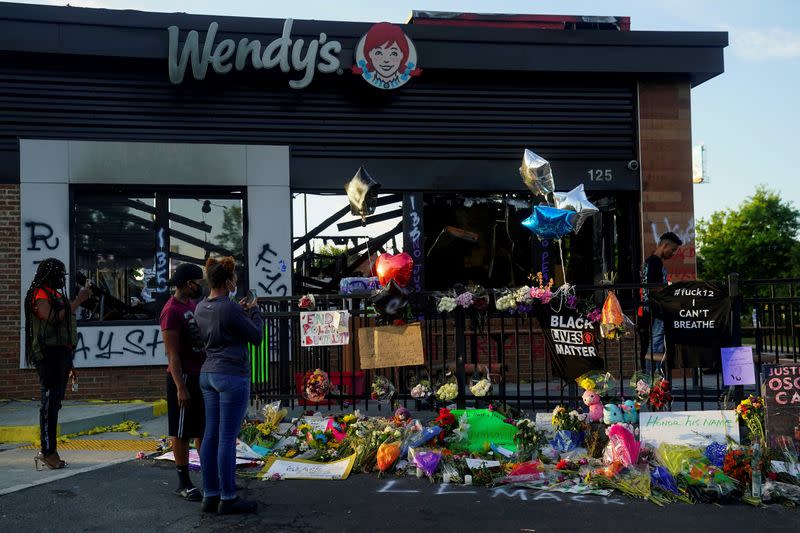 People take photos of a memorial to Rayshard Brooks at the Wendy's where he was shot and killed by police officers, in Atlanta