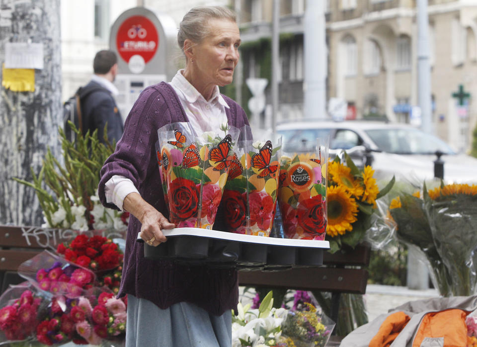 In this Sept. 5, 2013 photo, a florist carries flowers in trendy Savior Square in Warsaw, Poland. It has become one of the capital city’s trendiest places after political and economic reform and attracts tourists, students and professionals with its numerous cafes and leisurely ambiance. (AP Photo/Czarek Sokolowski)