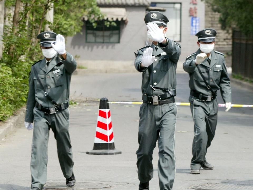 Three security guards wearing masks run out to prevent photographs from being taken at the entrance to the sealed off Ditan Hospital in Beijing, Friday, April 25, 2003.