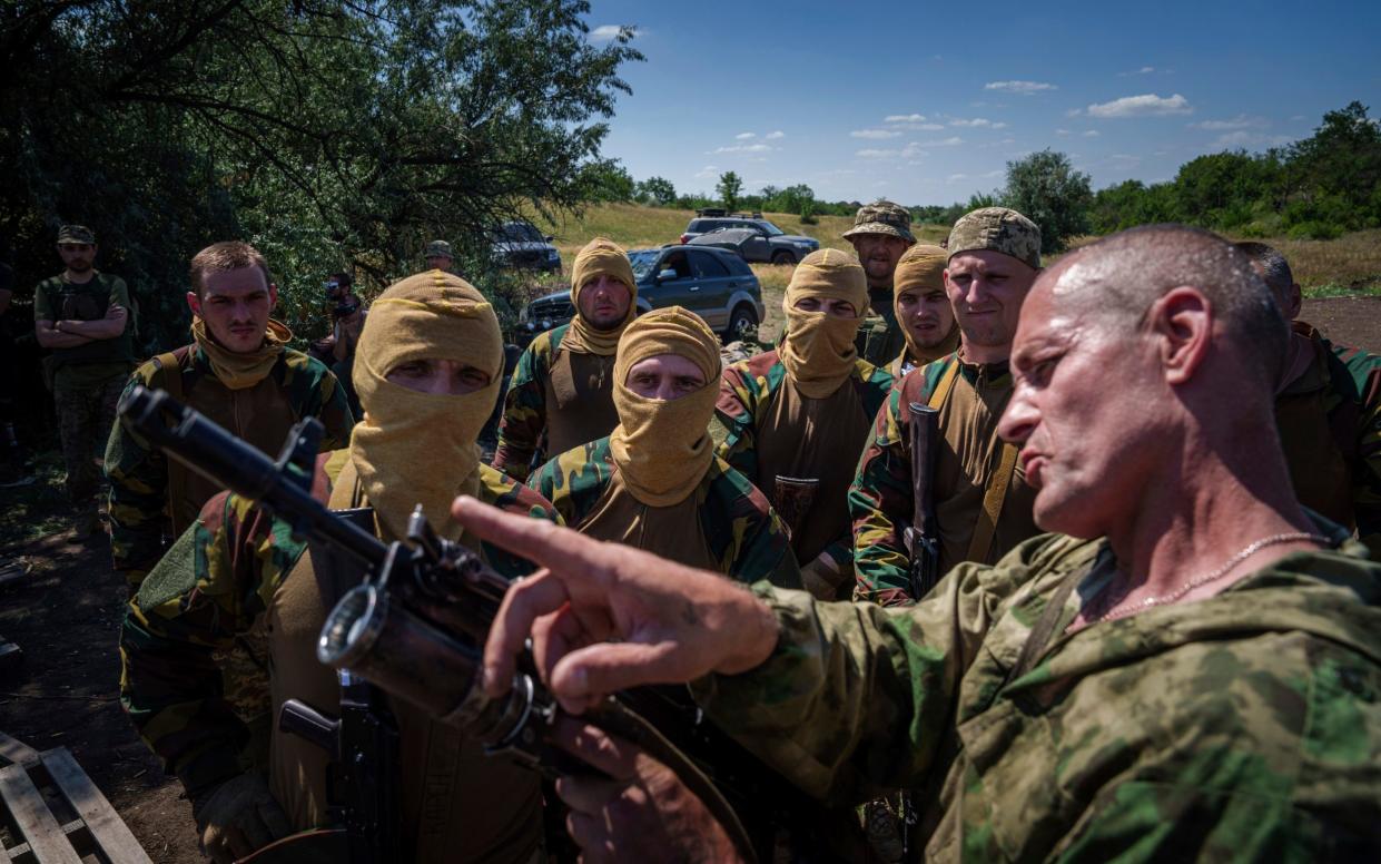 A Ukrainian military instructor of the Arey Battalion demonstrates to convict prisoners turned soldiers how to use a grenade launcher on a rifle in the Dnipropetrovsk region, Ukraine