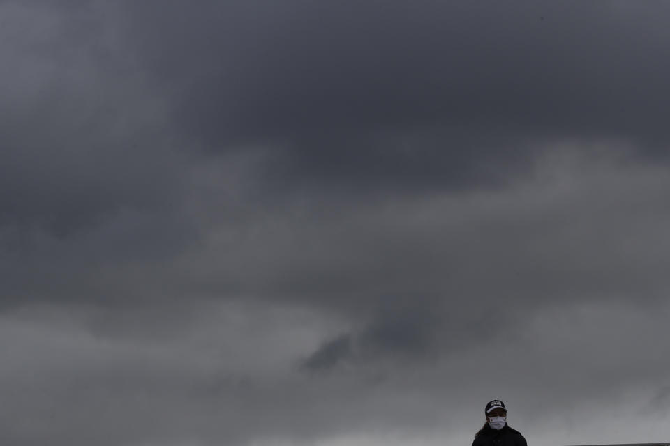 A lone spectator is silhouetted against rain clouds passing over third round matches of the French Open tennis tournament at the Roland Garros stadium in Paris, France, Saturday, Oct. 3, 2020. (AP Photo/Alessandra Tarantino)