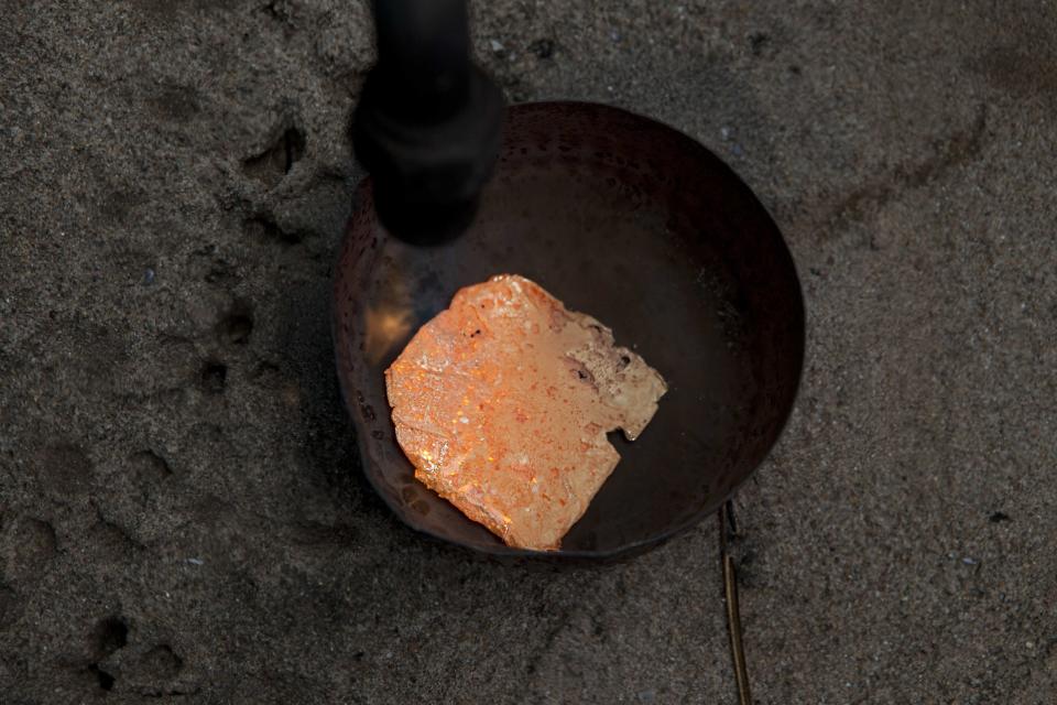 In this May 4, 2014 photo, a miner melts an amalgam of gold and mercury to burn off the mercury, in La Pampa in Peru's Madre de Dios region. This rudimentary process of extracting the gold from the amalgam, releases mercury vapors, adding to the contamination that is resulting in the deforestation of thousands of acres of the Amazon rainforest. Peru’s government declared all informal mining illegal on April 19 and began a crackdown, dynamiting their equipment. (AP Photo/Rodrigo Abd)