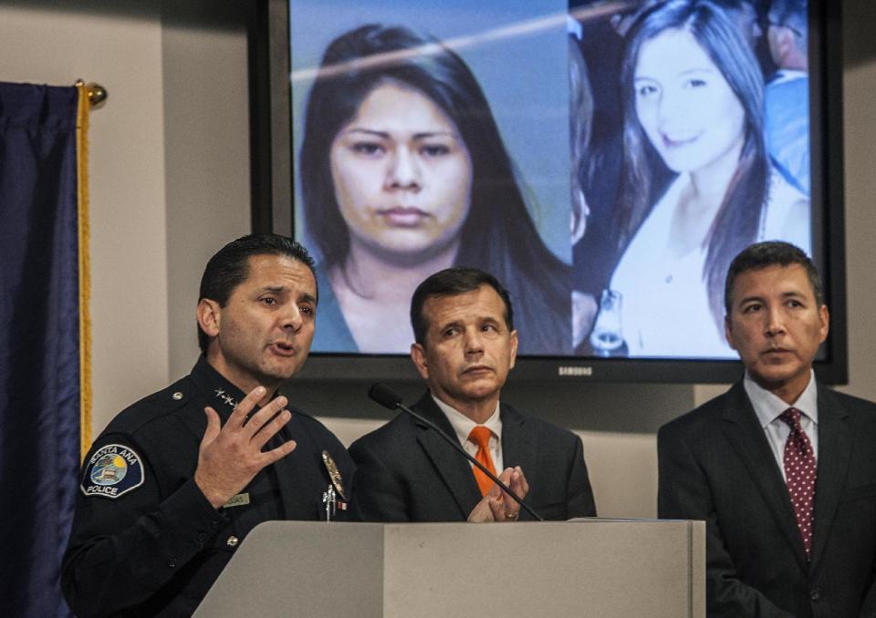 Santa Ana Police Chief Carlos Rojas, left, holds a news conference to announce that a second suspect had been arrested for investigation of murder in the case of beating victim Annie "Kim" Pham, Friday, Jan. 24, 2014 in Santa Ana, Calif., as Santa Ana mayor Miguel Pulido, center, and Santa Ana Councilman Vincent Sarmiento look on. Projected on the screen behind Rojas are images of Vanesa Zavala, left, who has been arrested in the case, and an unidentified woman, right, that police are looking for as a "person of interest" in the case. (AP Photo/The Orange County Register, Bruce Chambers) MAGS OUT; LOS ANGELES TIMES OUT