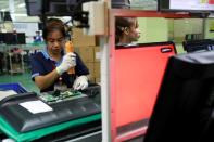 Migrant workers from Myanmar test the quality of monitors as they work on a TV assembly line at a factory in Bangkok