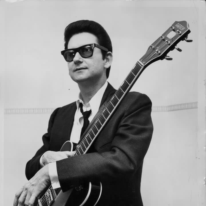 Roy Orbison wearing wayfarer shades and holding a guitar
