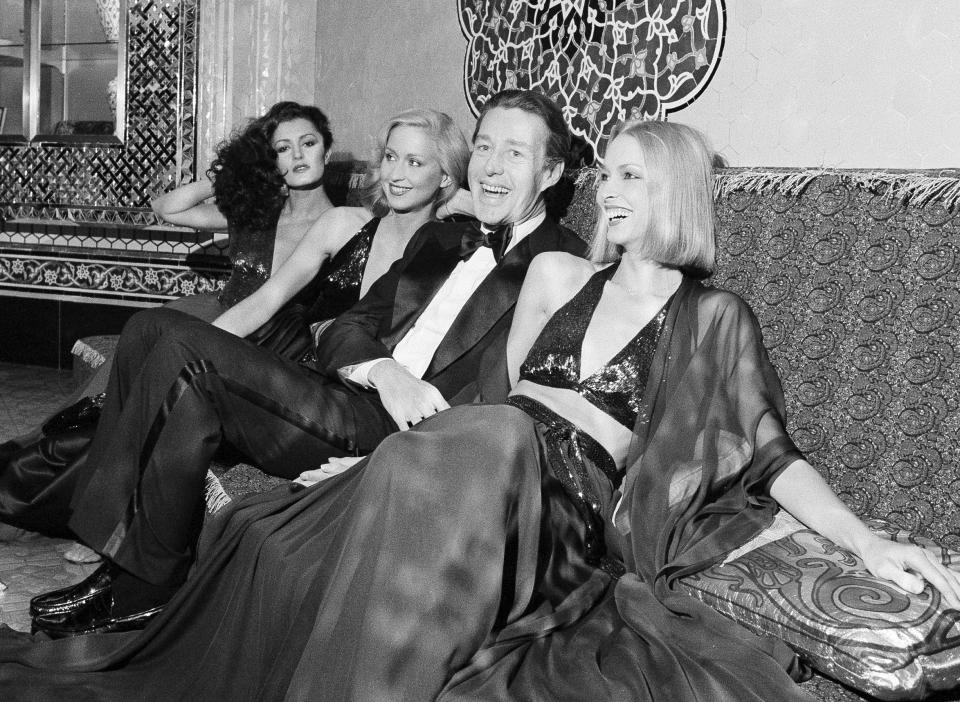 FILE - Designer Halston laughs with three of his models at the Iranian Embassy in Washington prior to the start of a benefit fashion show on on Oct. 5, 1977. A new series about the fashion designer, "Halston," premieres Friday on Netflix. (AP Photo/Charles Harrity, File)