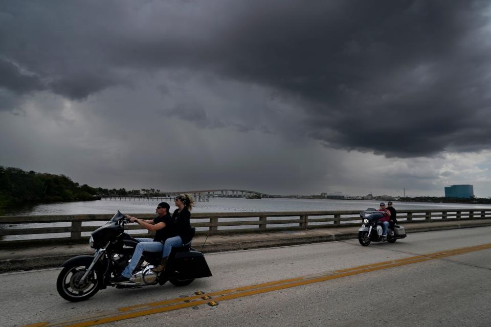 Bikers cross the Main Street bridge as storm clouds threaten just to the south during Bike Week in Daytona Beach, Sunday, March 3, 2024.