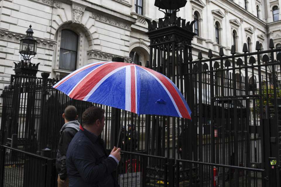 A man with a Union Flag themed umbrella walks past the gates of Downing Street, in London, Monday, Oct. 21, 2019. There are just 10 days until the U.K. is due to leave the European bloc on Oct. 31.(AP Photo/Alberto Pezzali)