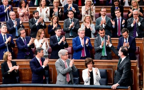 Spanish Prime Minister Mariano Rajoy (bottom R) acknowledges applause from Popular Party's members of parliament  - Credit: PIERRE-PHILIPPE MARCOU /AFP