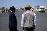 Members staff of U.S Aid stand as Gaza aid on a truck is about to enter a U.S ship, at the port of Larnaca, Cyprus, Wednesday, June 26, 2024. An official with the U.S. humanitarian assistance agency USAID says thousands of tons of food, medicines and other aid piled up on a Gaza beach isn't reaching those in need because of a dire security situation on the ground where truck drivers are either getting caught in the crossfire or have their cargo seized by "gang-like" groups. (AP Photo/Petros Karadjias)