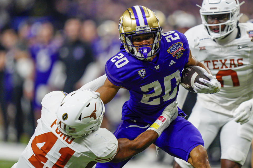 FILE - Texas linebacker Jaylan Ford (41) tries to tackle Washington running back Tylin "Tybo" Rogers (20) during the Sugar Bowl CFP NCAA semifinal college football game, Jan. 1, 2024, in New Orleans. Rogers was arrested Friday, April 5, and charged Tuesday, April 9, with raping two women in Seattle. Court documents say he played in two College Football Playoff games for the school after the allegations were known to the university. (AP Photo/Jacob Kupferman, File)