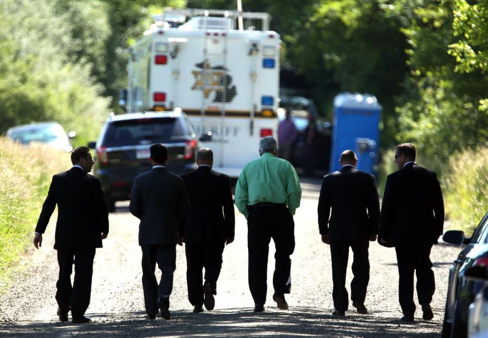 FBI and local law enforcement officers walk back to their staging area after holding a news conference where they told the media they had given up their search for the remains of Jimmy Hoffa in an overgrown farm field in Oakland Township on June 19, 2013.