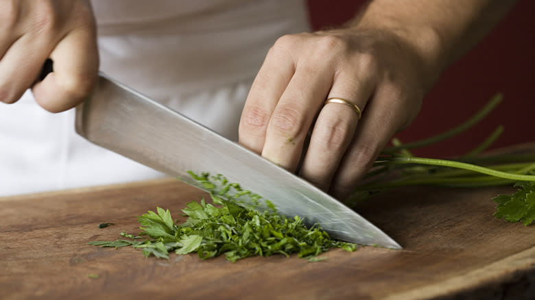 person chopping fresh green herbs