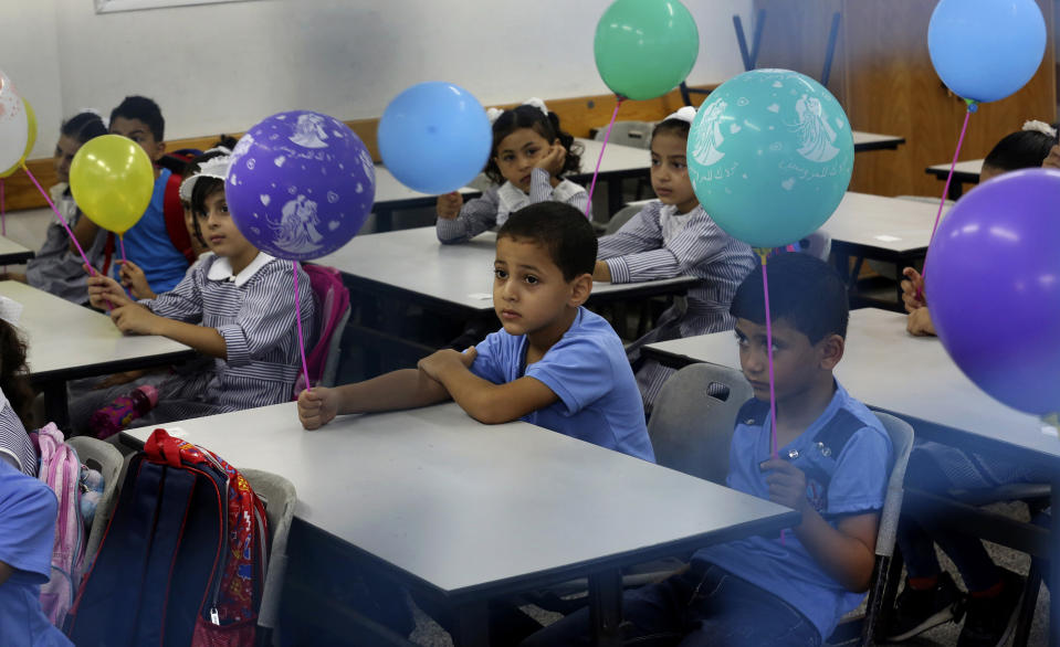 Students wave balloons on the first day of the new school year at the United-Nation run Elementary School at the Shati refugee camp in Gaza City, Saturday, Aug. 8, 2020. Schools run by both Palestinian government and the U.N. Refugee and Works Agency (UNRWA) have opened almost normally in the Gaza Strip after five months in which no cases of community transmission of the coronavirus had been recorded. (AP Photo/Adel Hana)