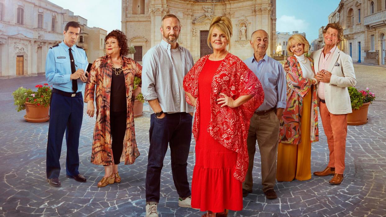  The Madame Blanc Mysteries season 3 cast in a group shot set against the backdrop of Sainte Victoire's main square: Alex Gaumond as Caron, Sue Vincent as Gloria, Steve Edge as Dom, Sally Lindsay as Jean, Sue Holderness as Judith and Robin Askwith as Jeremy. 
